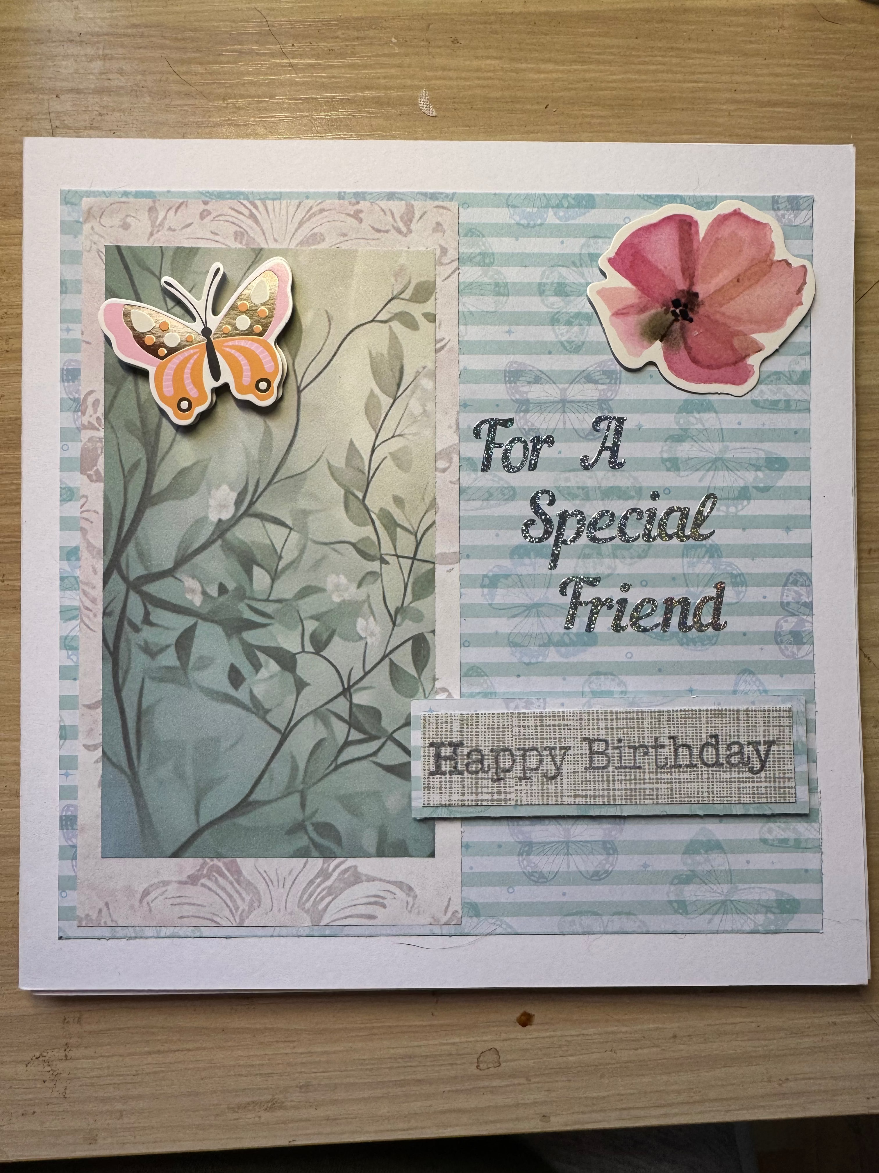 Handmade birthday card with butterfly and floral design on a wooden surface