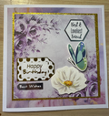 Greeting card with floral design, butterfly, and text on a wooden surface