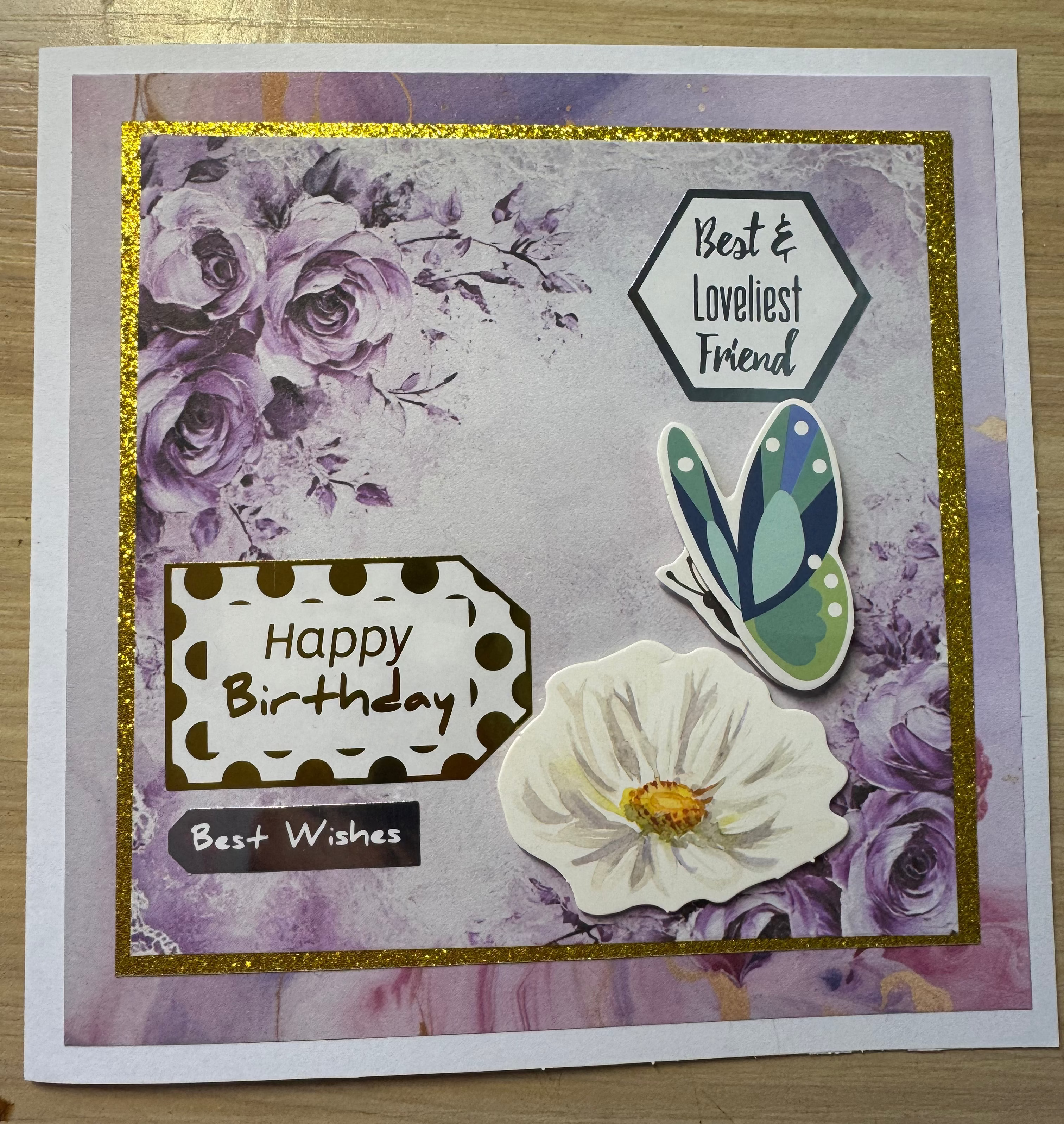 Greeting card with floral design, butterfly, and text on a wooden surface