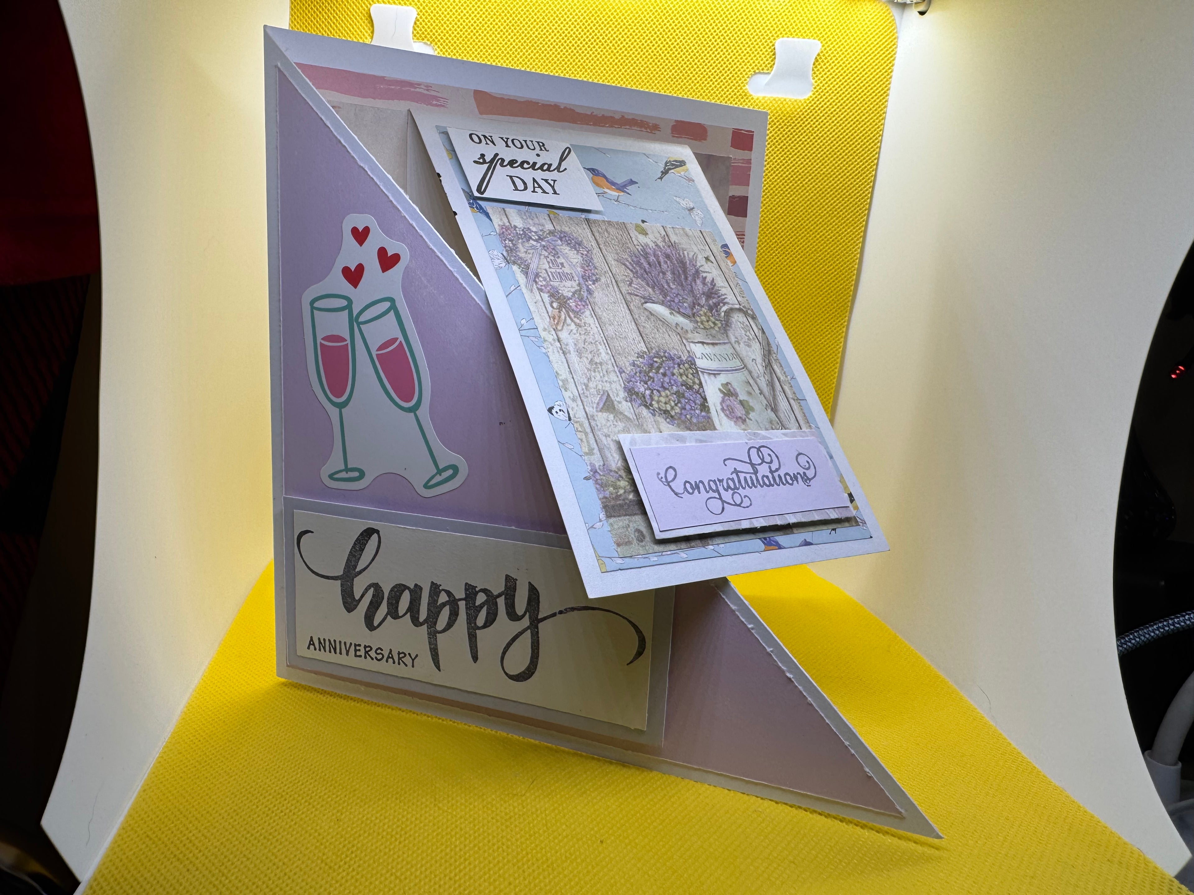 Card with 'Happy Anniversary' and 'Congratulations' text on a yellow stand.